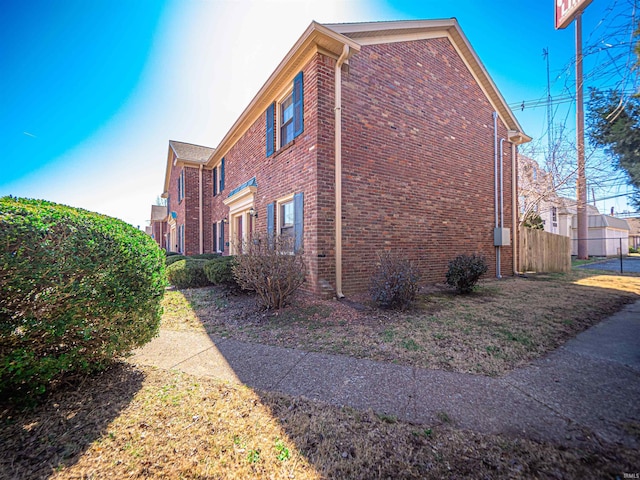 view of property exterior featuring brick siding and fence