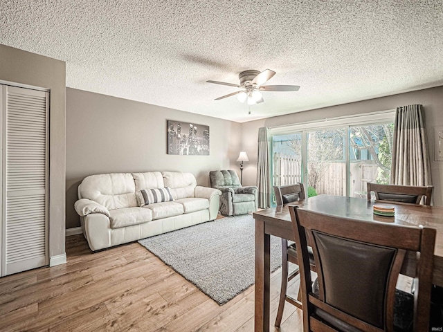 living area with a textured ceiling, wood finished floors, baseboards, and ceiling fan