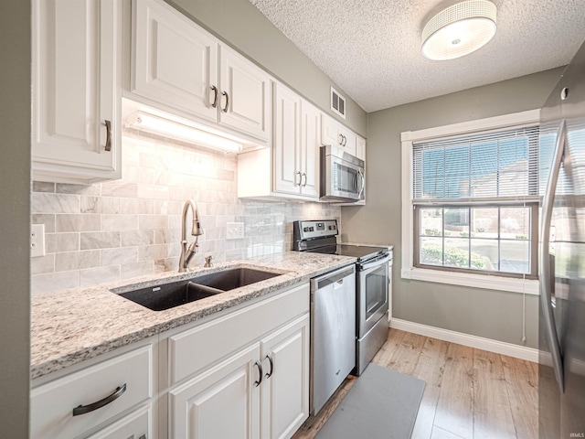 kitchen featuring tasteful backsplash, appliances with stainless steel finishes, white cabinetry, and a sink