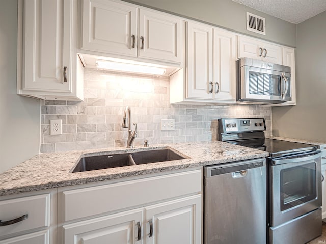 kitchen featuring visible vents, white cabinetry, stainless steel appliances, and a sink