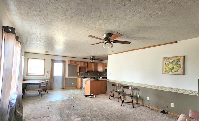 kitchen with brown cabinetry, a peninsula, a textured ceiling, and light carpet