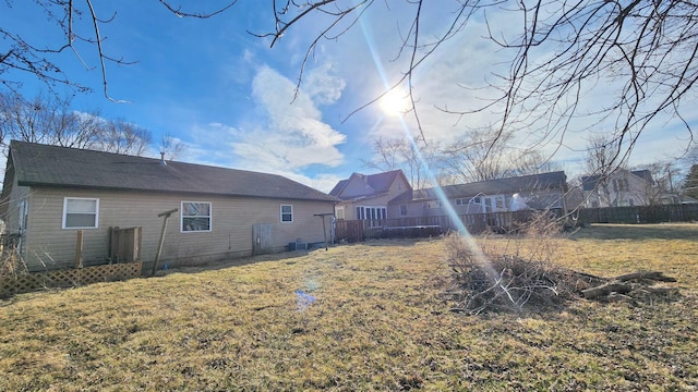 back of house with fence, a lawn, and a wooden deck