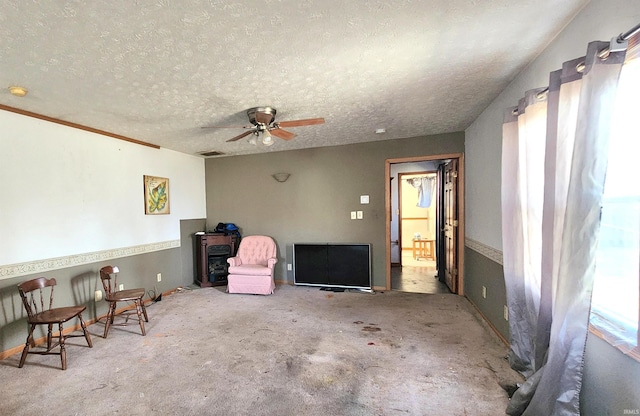 living area featuring ceiling fan and a textured ceiling