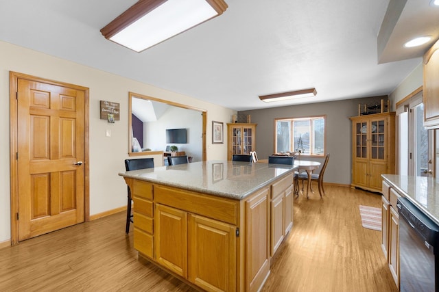 kitchen featuring light wood-style floors, baseboards, black dishwasher, and a center island