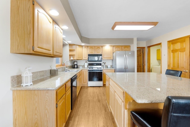 kitchen with light wood-type flooring, black appliances, a breakfast bar area, and light brown cabinetry