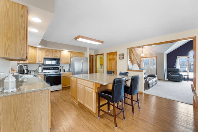 kitchen featuring black microwave, light brown cabinetry, freestanding refrigerator, white electric range, and a sink