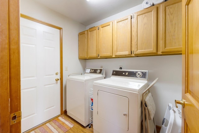 laundry area with light wood-type flooring, cabinet space, and washer and clothes dryer