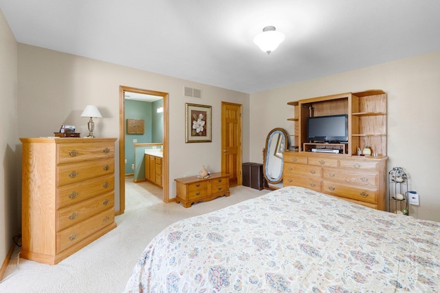 bedroom with visible vents, light carpet, and ensuite bathroom