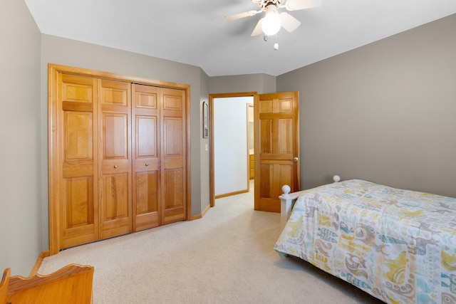 carpeted bedroom with a closet, baseboards, and a ceiling fan