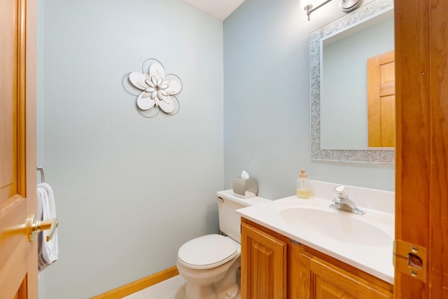 half bathroom featuring baseboards, toilet, and vanity