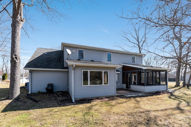 back of property with a lawn, roof with shingles, and a sunroom