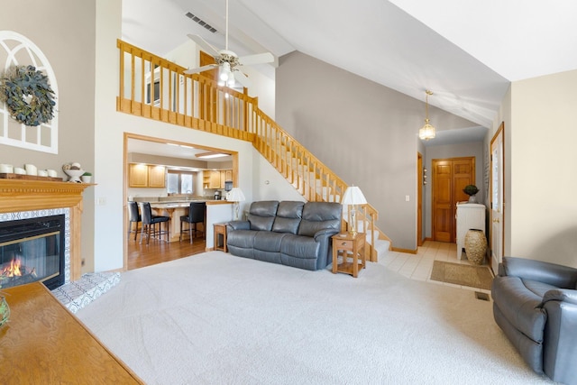 living area with visible vents, stairway, a fireplace, lofted ceiling, and light colored carpet