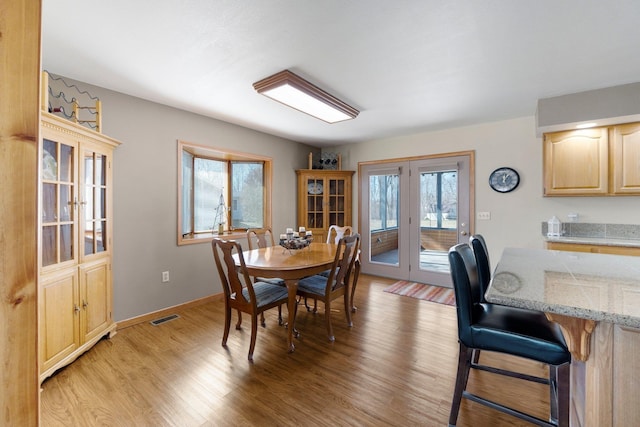 dining room featuring light wood-style floors, french doors, visible vents, and baseboards