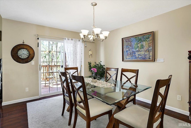 dining space featuring a chandelier, baseboards, and wood finished floors