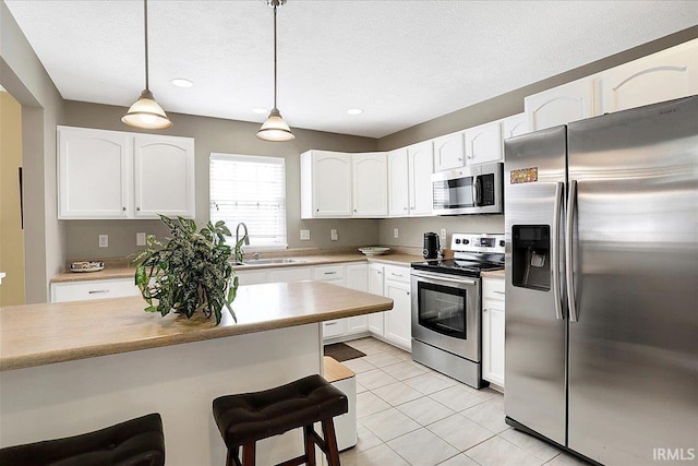 kitchen featuring white cabinetry, a kitchen breakfast bar, stainless steel appliances, and a sink