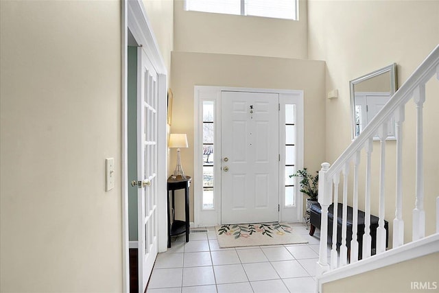 entryway featuring light tile patterned floors, stairway, and a towering ceiling