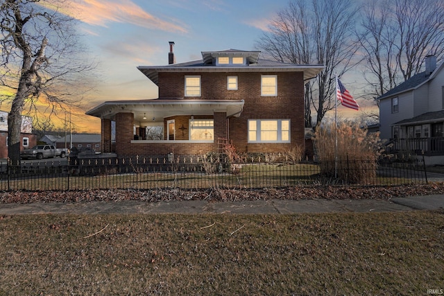 view of front of house with a porch, brick siding, and a fenced front yard