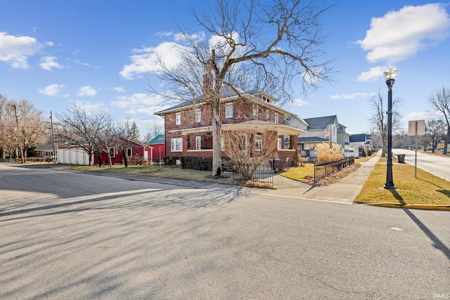 traditional style home featuring brick siding, fence, and a residential view