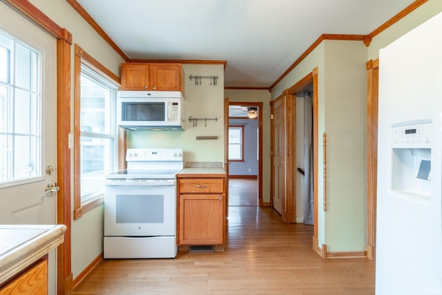 kitchen with light wood-type flooring, white appliances, baseboards, and crown molding