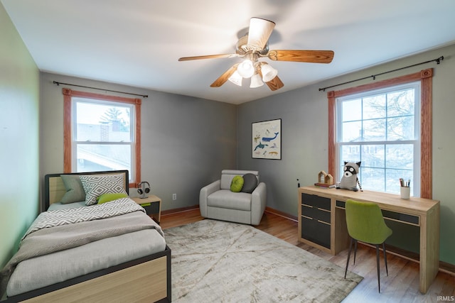 bedroom with multiple windows, baseboards, and wood finished floors