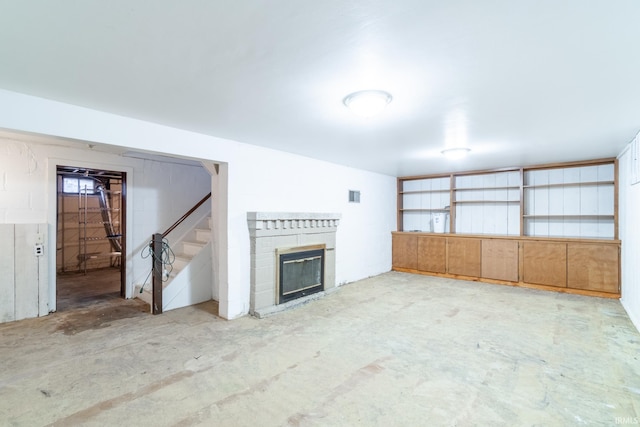 unfurnished living room featuring visible vents, a fireplace, stairs, and concrete flooring