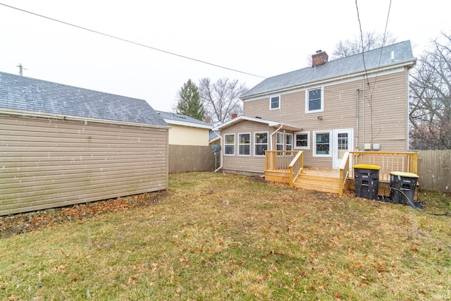 back of property featuring a lawn, a deck, a chimney, and fence