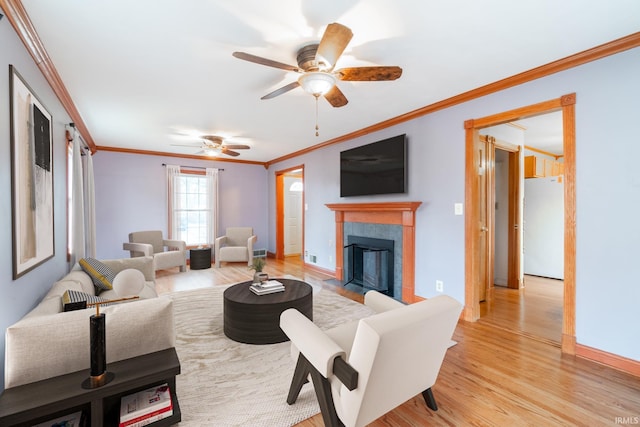 living area featuring light wood-style flooring, a fireplace with flush hearth, baseboards, and ornamental molding