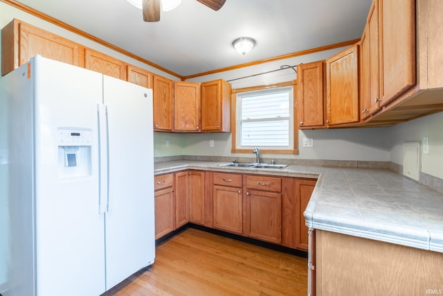 kitchen featuring tile countertops, ceiling fan, a sink, white refrigerator with ice dispenser, and light wood-type flooring