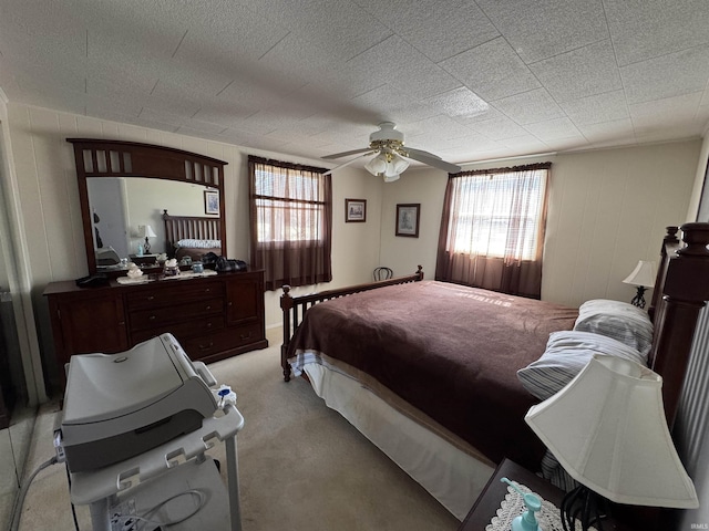 bedroom featuring a ceiling fan, multiple windows, and light colored carpet