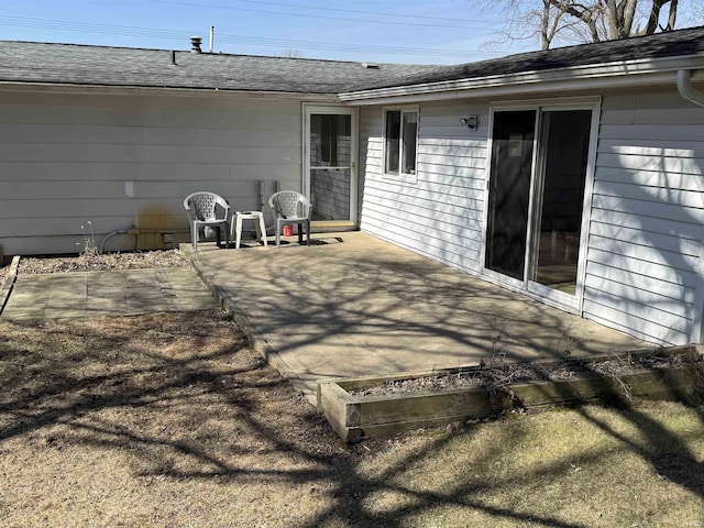 back of house with a patio and roof with shingles