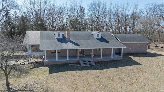 rear view of house featuring a porch, brick siding, and a chimney