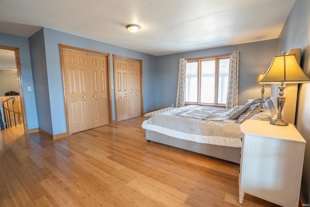 bedroom featuring light wood-style floors, baseboards, and two closets