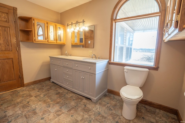 full bath featuring a sink, baseboards, toilet, and double vanity