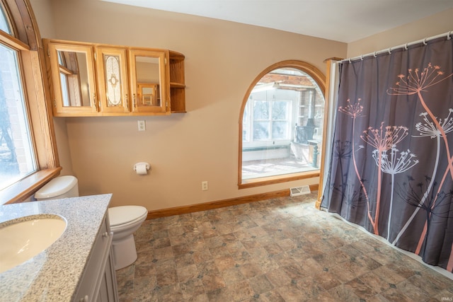 full bathroom with visible vents, stone finish flooring, baseboards, toilet, and vanity