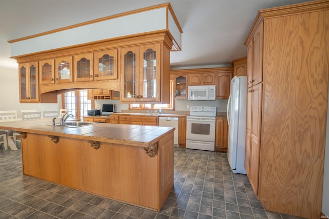 kitchen featuring white appliances, tile countertops, a breakfast bar, a sink, and glass insert cabinets