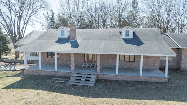 view of front of home featuring brick siding, covered porch, a chimney, and a shingled roof