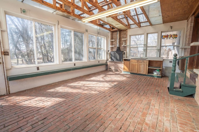 unfurnished sunroom featuring a sink and a wood stove