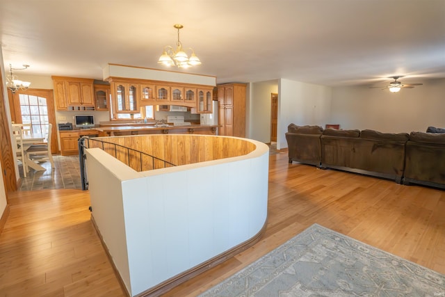 kitchen featuring glass insert cabinets, a kitchen island, hanging light fixtures, and light wood finished floors