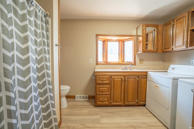 washroom featuring visible vents, baseboards, washing machine and dryer, light wood-type flooring, and laundry area