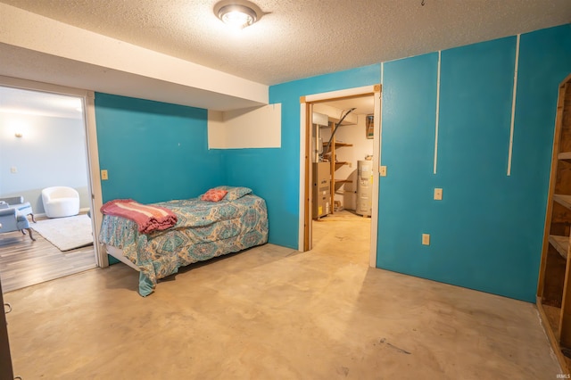 bedroom featuring water heater, concrete flooring, and a textured ceiling