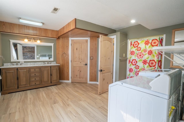 clothes washing area with washer and clothes dryer, laundry area, light wood-type flooring, and a sink