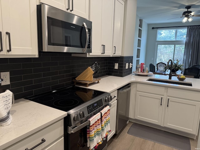 kitchen featuring a ceiling fan, a sink, white cabinets, appliances with stainless steel finishes, and backsplash