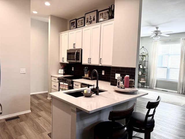 kitchen with tasteful backsplash, visible vents, light countertops, appliances with stainless steel finishes, and a sink