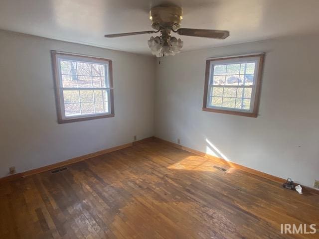 spare room featuring a wealth of natural light, a ceiling fan, baseboards, and wood finished floors