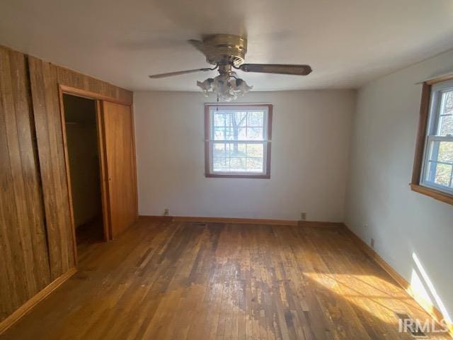 unfurnished bedroom featuring a closet, wood-type flooring, baseboards, and a ceiling fan