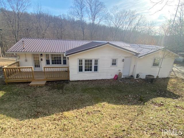 rear view of house featuring metal roof, a yard, and a deck