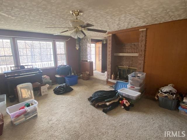 interior space featuring carpet flooring, a brick fireplace, and a ceiling fan