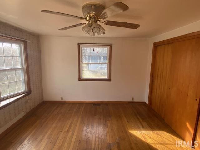 unfurnished bedroom with light wood finished floors, baseboards, wallpapered walls, and a closet