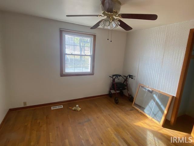 empty room featuring wood finished floors, visible vents, and baseboards