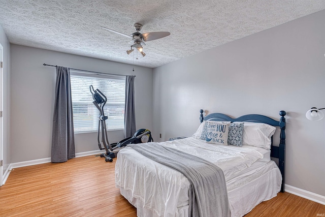 bedroom featuring a textured ceiling, light wood-type flooring, baseboards, and a ceiling fan